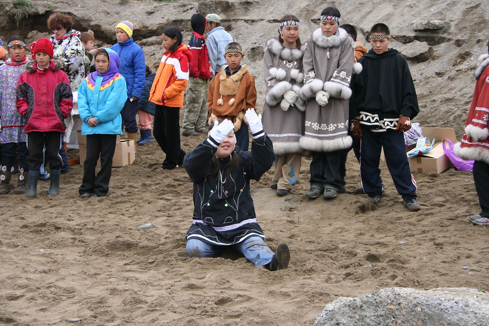 A young dancer in ceremonial parka lifts her hands to the low sun during the afternoon’s celebration, Lorino, June 2008. Photograph by Pam King.