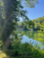 Eye-level view of riverside camping pitch with tents and trees