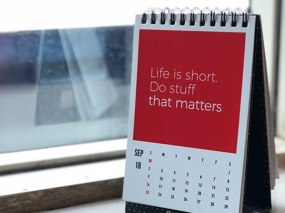 Desk calendar with "Life is short. Do stuff that matters" text on a red background. Date shows September 18. Blurred window in background.