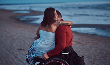 loving-couple-woman-sits-her-husband-s-lap-resting-beach-against-background-bright-dawn.jp