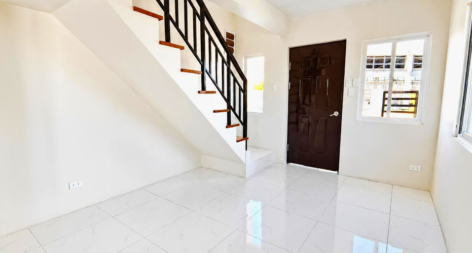 Bright modern interior featuring a wooden‑step staircase, white tiles, neutral walls, and natural light from two windows.