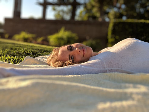 Close-up of the author Alexandria Light laying on a picnic blanket on the grass in a park