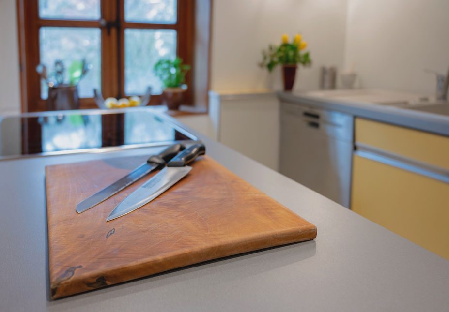 Zwei Messer auf einem Schneideblock und Blick auf das Ceranfeld, die Spülmaschine und das Waschbecken.