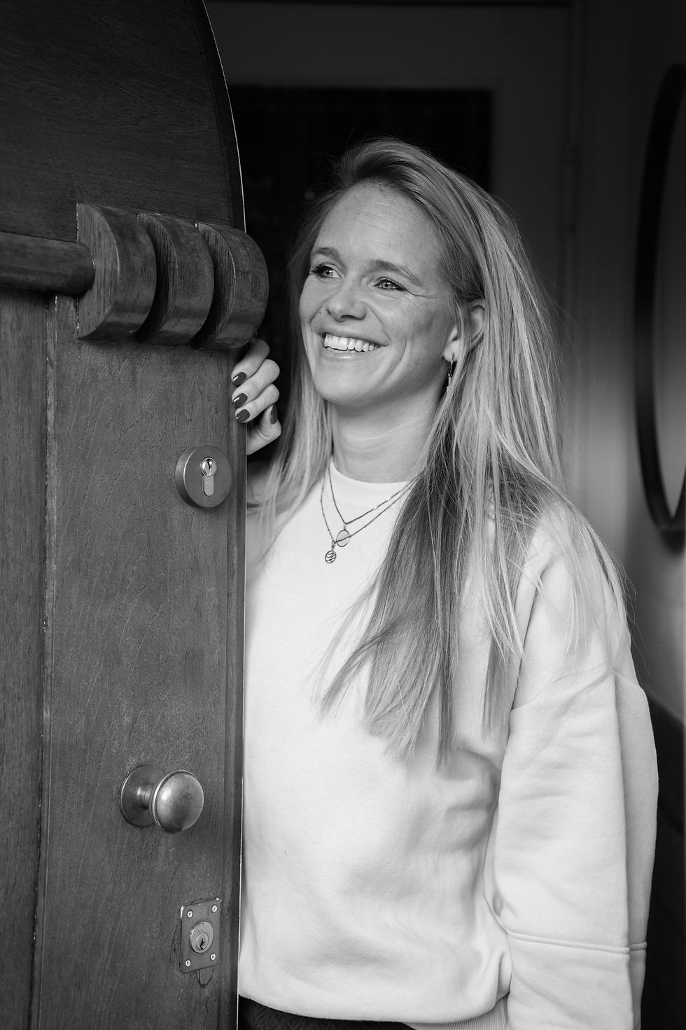 Blonde vrouw glimlach opent een deur vriendelijk welkom