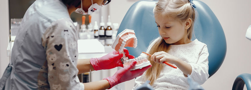 Dentist shows child proper brushing using dental model