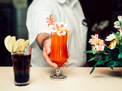 Bartender offering a colorful cocktail with flower garnish on a bar Theme 44