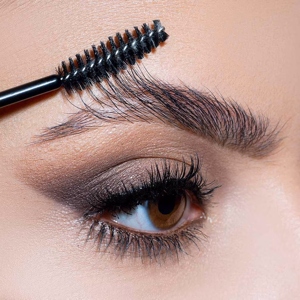 A close up of a women's eye as she brushed out her eyebrow