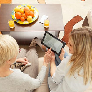 girl with older woman showing them how to use an ipad