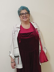 Smiling woman with blue hair in burgundy jumpsuit, white jacket