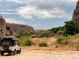 Een GreenTracers-4x4 op een rotsachtige piste tussen kliffen en mediterrane begroeiing.