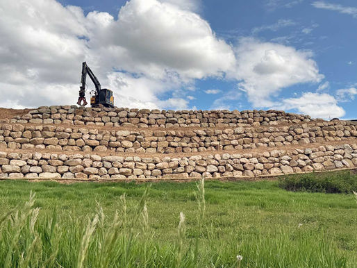 rock retaining wall with an excavator on top