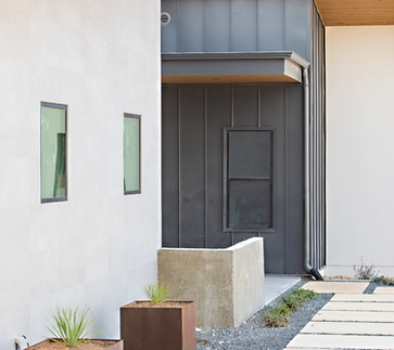 Modern home exterior, metal siding, gravel path, planters