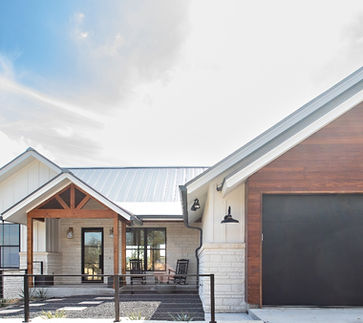 Modern home with white and wood siding, metal roof, and a black garage door