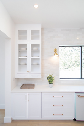 Bright white kitchen with glass cabinets and gold hardware