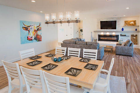 Modern open-concept dining room, living area, cow painting, and sleek fireplace.