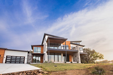 Modern luxury house with wood and stone accents under blue sky.