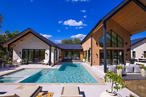 Modern L-shaped house with large pool and outdoor living area.