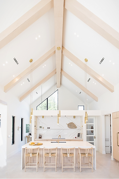 Modern kitchen with vaulted ceiling, exposed wooden beams, and gold fixtures.