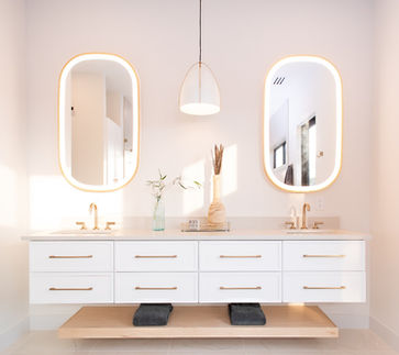 Modern double bathroom vanity with oval backlit mirrors and gold fixtures.