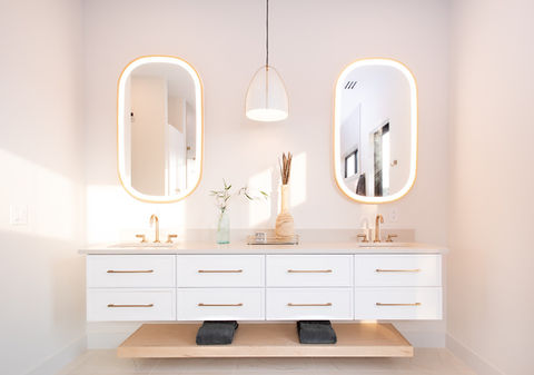 Modern bathroom with white floating vanity, dual sinks, and backlit mirrors.