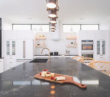 Contemporary kitchen with large dark island, cheese, crackers, strawberries.