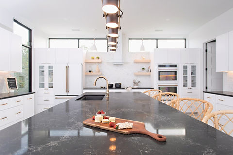 Modern kitchen island with charcuterie board, white cabinets, gold accents.
