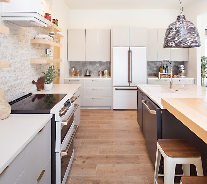 Modern kitchen with white cabinets, wood floors, island, and appliances.