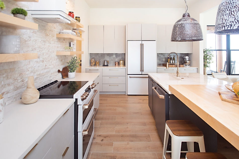 Modern kitchen with white cabinets, wood floors, island, and appliances.