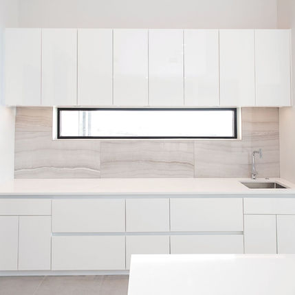 Modern white kitchen Interior Design with sleek cabinets, horizontal window, sink.