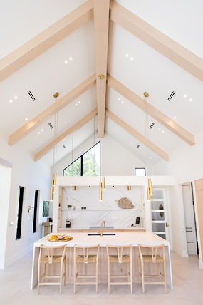 Modern kitchen with white vaulted ceiling, exposed beams, large island.