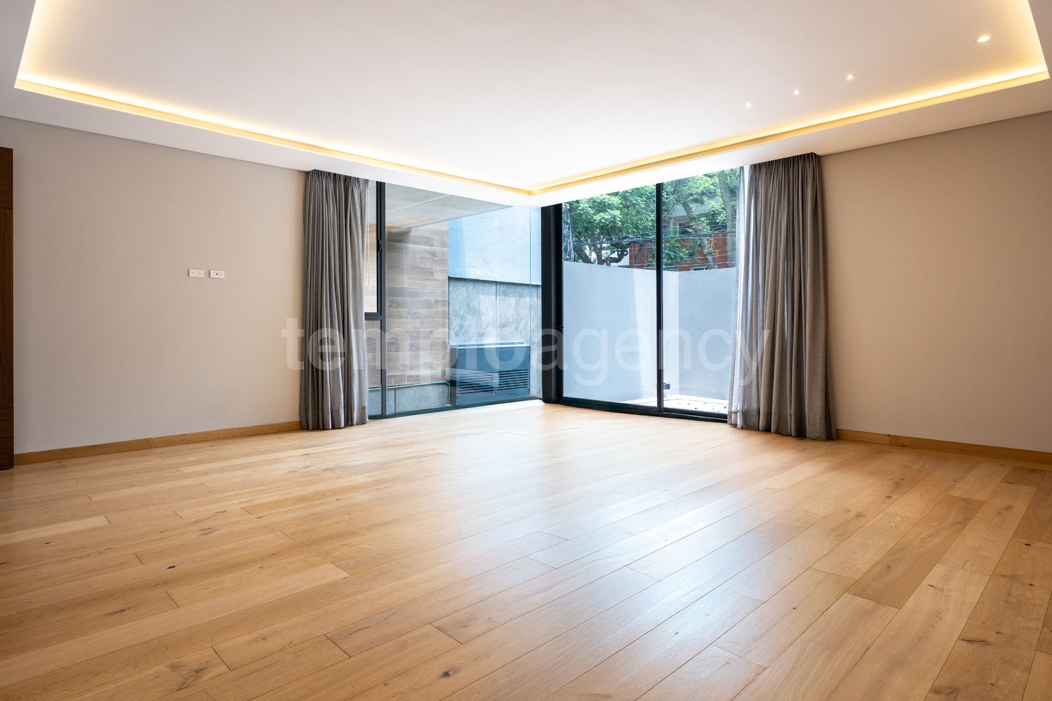 Interior del garden house de 3 Picos I, con piso de madera y ventanales hacia el patio