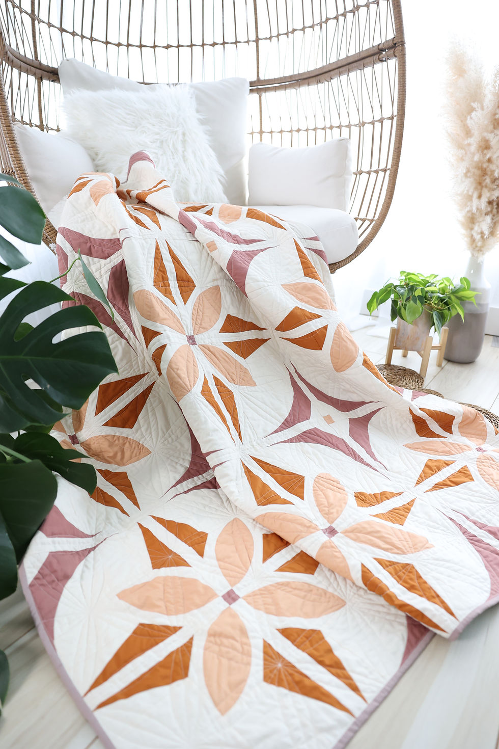 Bloom And Glow Quilt, a modern flower quilt pattern, draped in an egg chair.