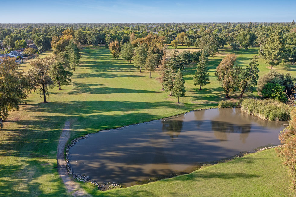 an aerial view of a golf course with a pond in the middle