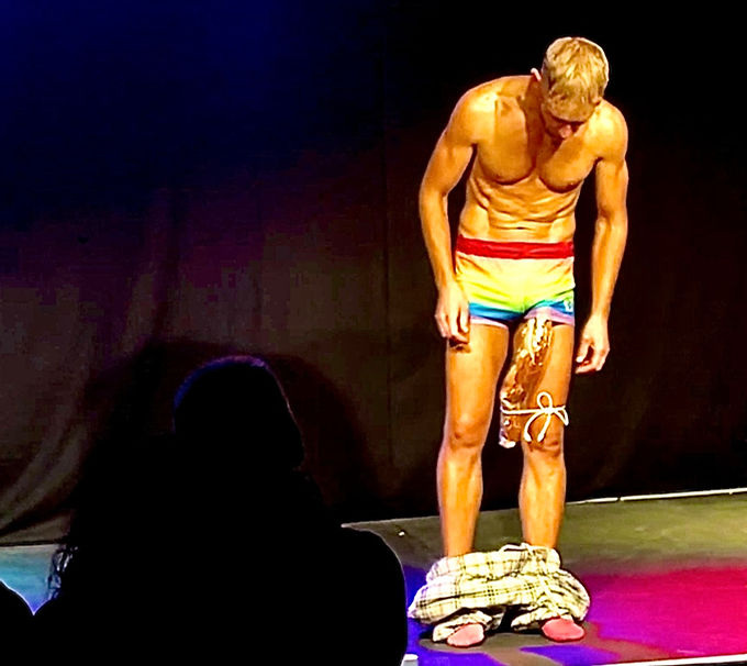 LGBTQ+ comedian Xander Platz on Stage at Edinburgh Fringe Festival with a massive bagette attched to his thigh