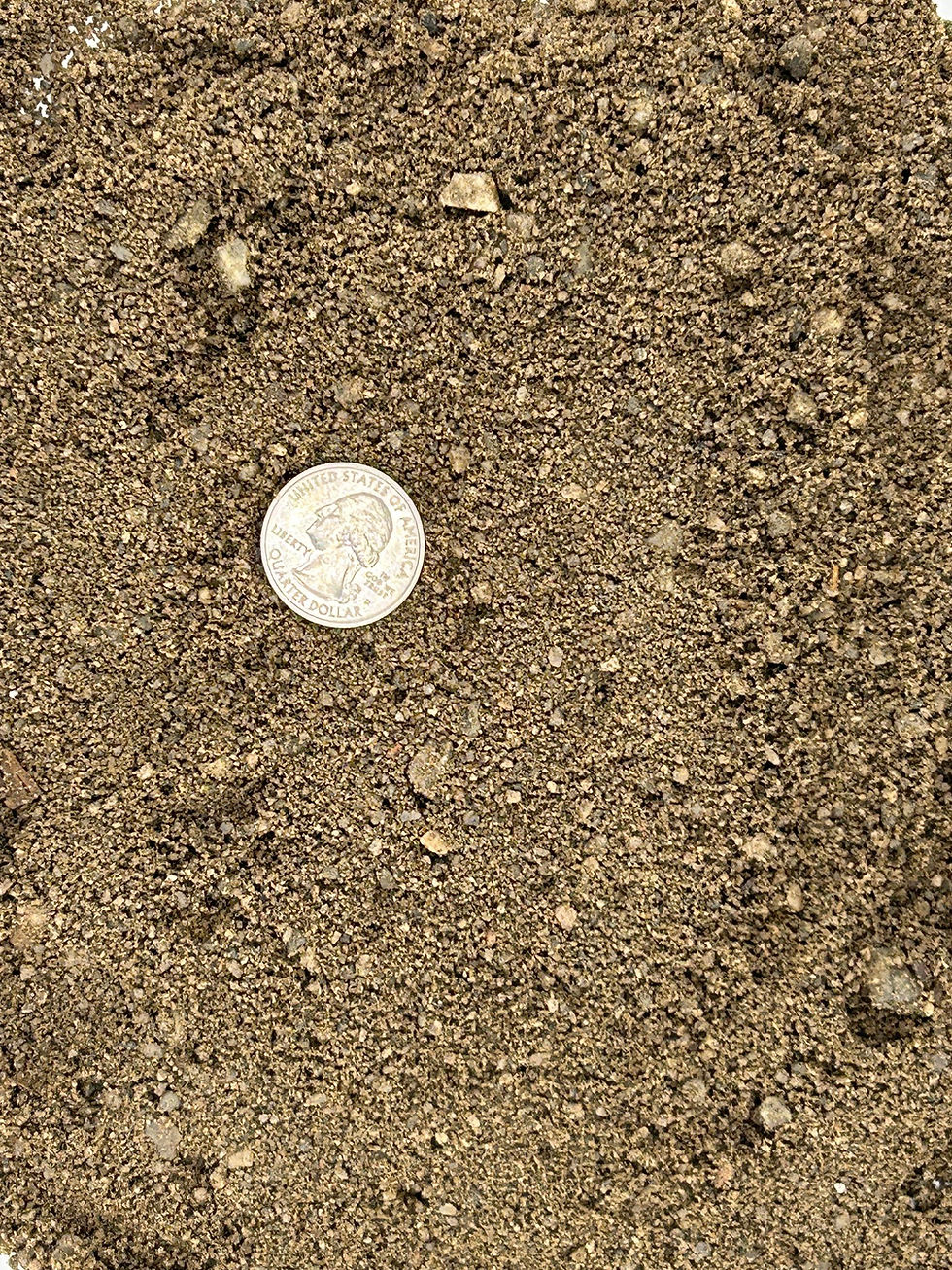 image shows a pile of finely grained fill sand with a brown grey color and a quarter for material size comparison