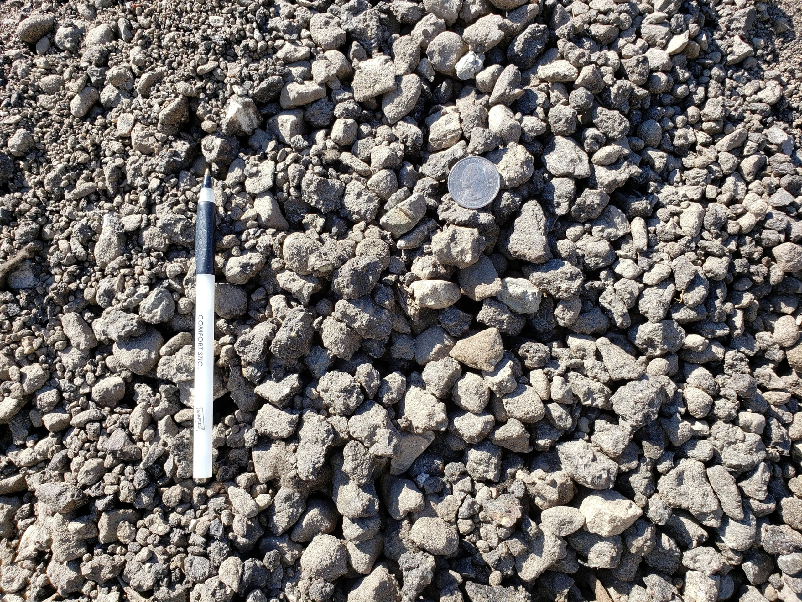 Image shows Coarse concrete mix and gray in color with a quarter for material size comparison