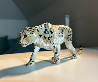 ručně modelovaná socha sněžného leoparda v chůzi.