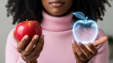 Woman holds a red apple in one hand and a glowing holographic apple in the other, wearing a pink sweater against a neutral background.