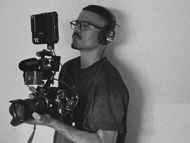 Adilson Santos nos bastidores de um trabalho segurando uma câmera
