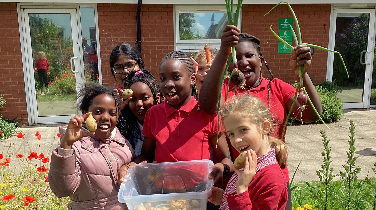 Children holding homegrown potatoes and onions.