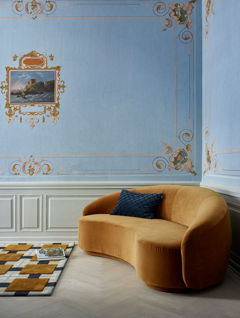 Gul soffa mot en himmelsblå vägg