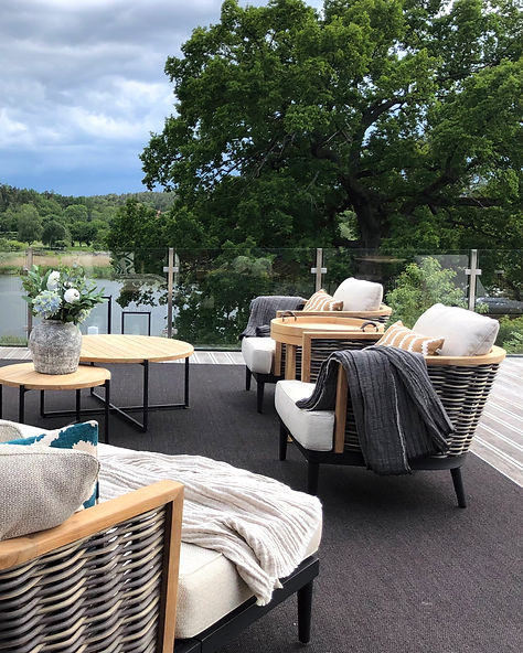Loungemöbler i konstrotting, teak och stål från Slettvoll, Underhållsfria dynor och kuddar från Chhattwal. Takterrass med glasräcke. Ljuslyktor i svart stål. Kruka med hortensior. Linnefilt. Matta för utomhusbruk.