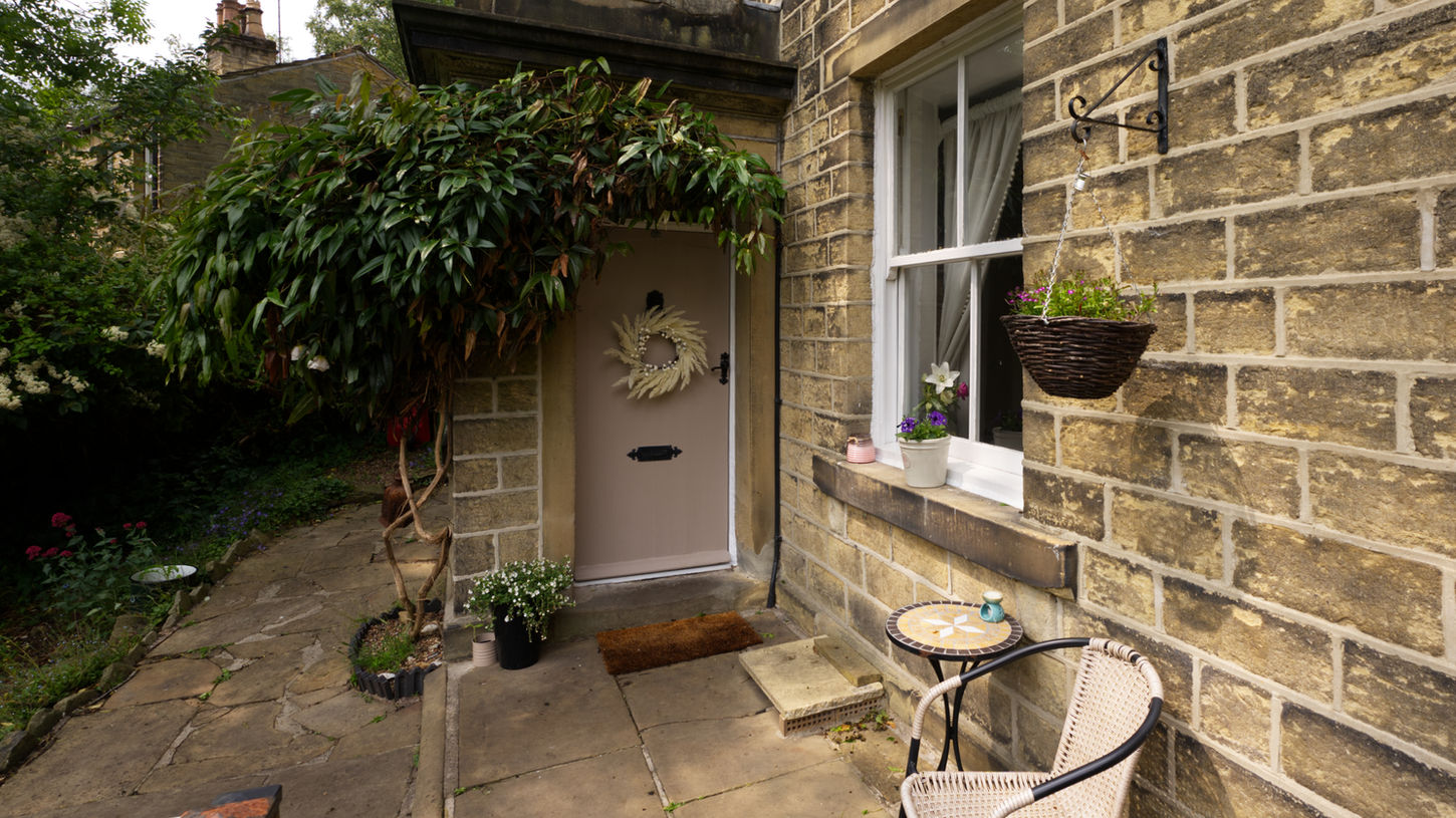 16mm shot of the front entrance to a property with a small table and chair to sit out in the front garden