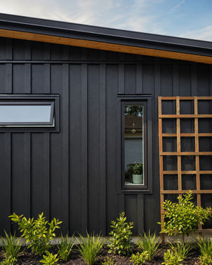 Black clad wall of Japavarian Blades with vertical window, wood trellis, planting, and warm wood soffit.