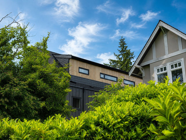 Ansoku multiplex housing in Vancouver seen from a landscaped garden, with cedar cladding, black shingles, and West Coast greenery.