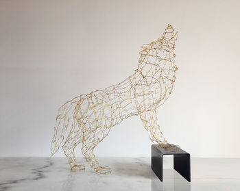 Sculpture en fil de laiton d'un loup entrain de hurler, les 2 pattes avant reposant sur un socle en acier. 