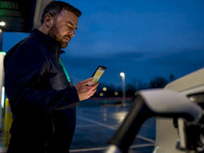Driver checking rapid charger status at dusk