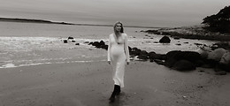 artistisk sorthvitt bilde av en gravid kvinne som går på stranden en stormfull dag