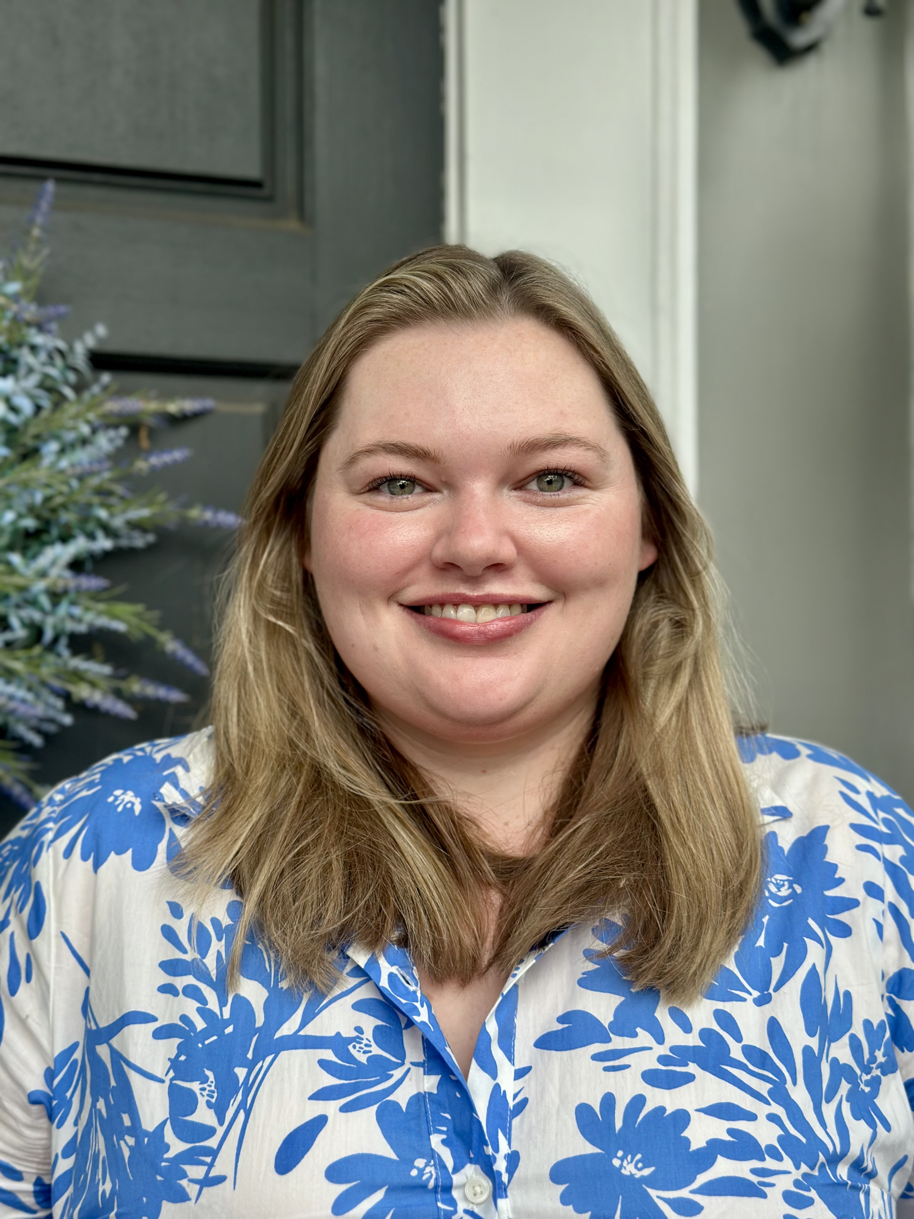 closeup headshot of Elizabeth Buckner wearing a blue and white floral shirt smiling