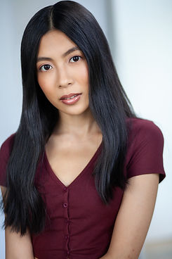 Professional actor Portrait of Nightingale (she/her) with medium length black hair.  She is wearing a burgandy button short.
